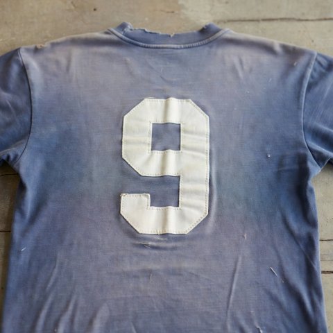 The back of a faded cotton football shirt with a large sewn-on number nine